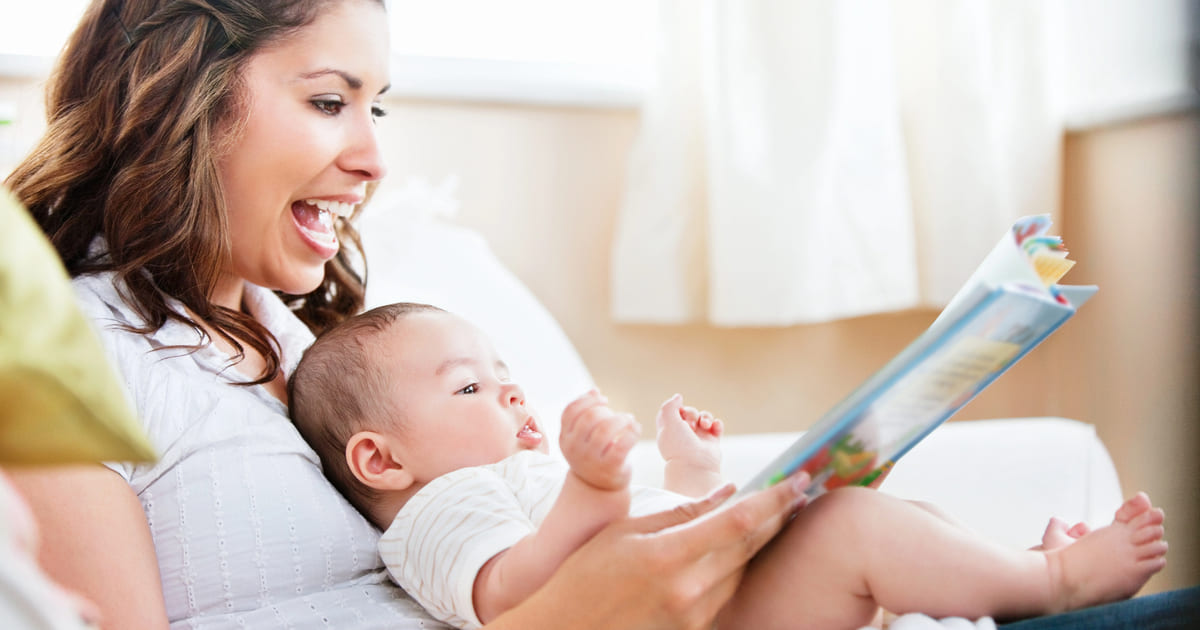 La lettura precoce nei bambini è importante: nella foto una mamma legge a un neonato un libro